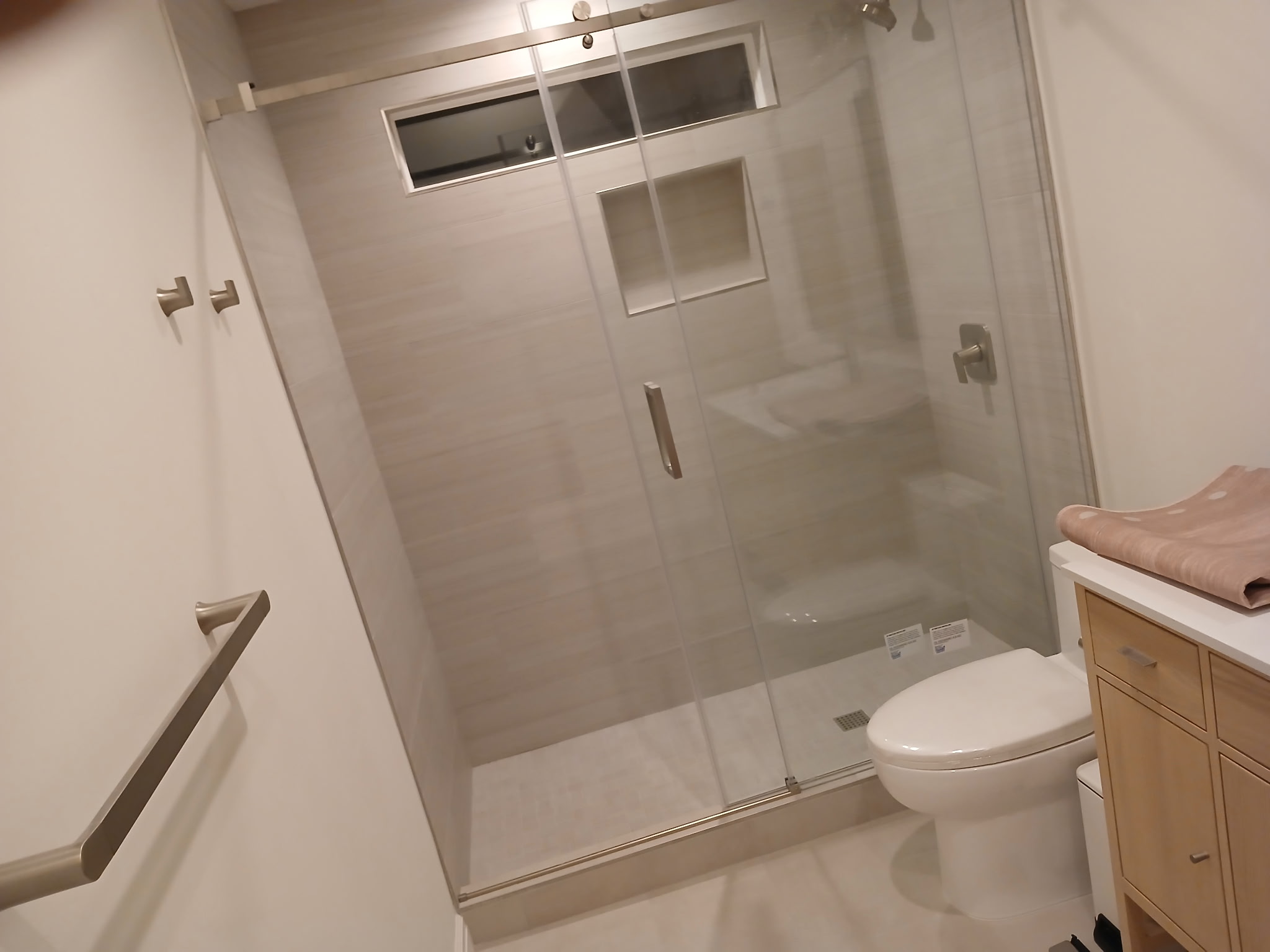 Completed bathroom with large glass-door tile shower, modern vanity, and toilet