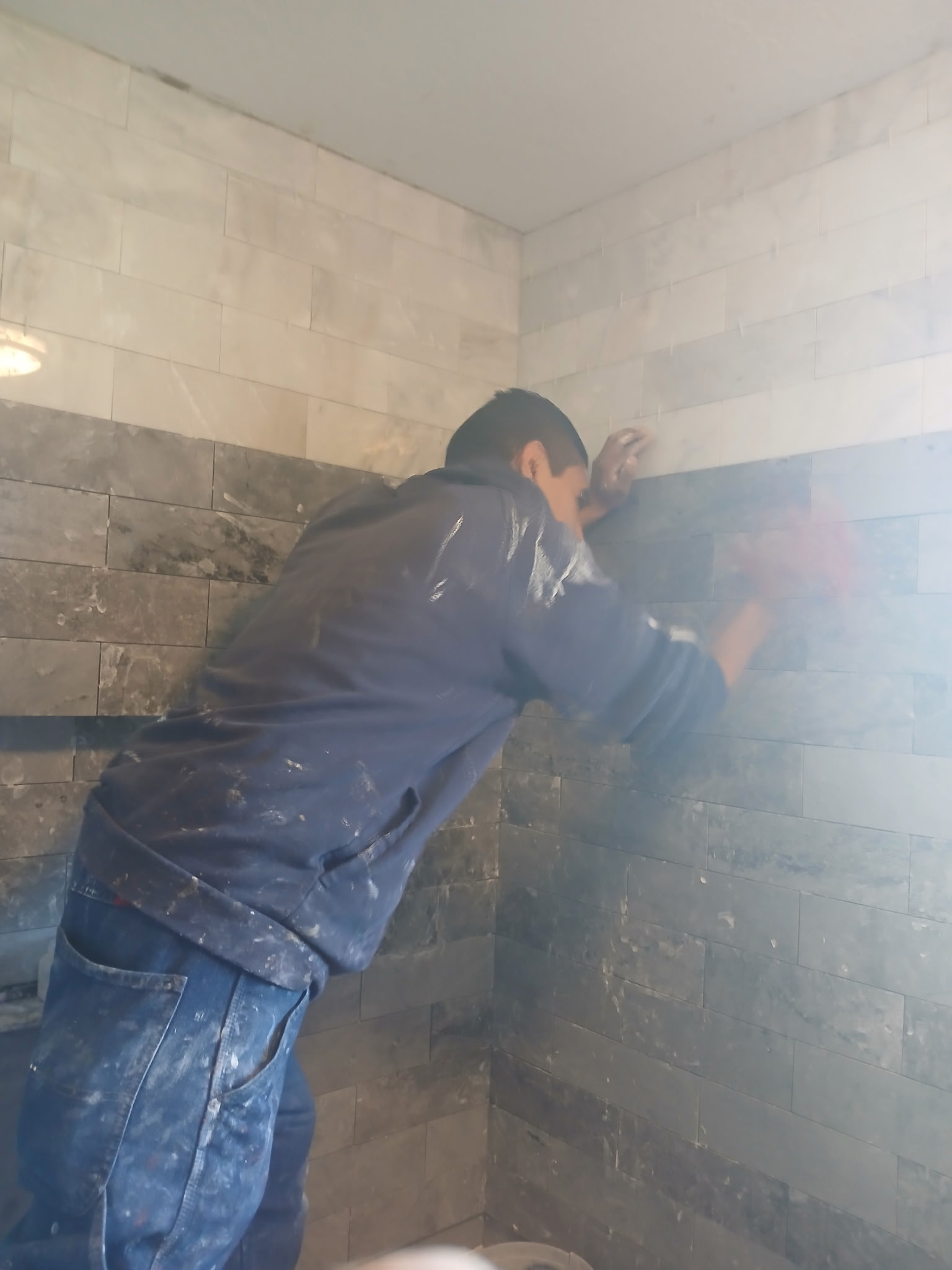 Tile installer carefully placing stone tile in a shower enclosure