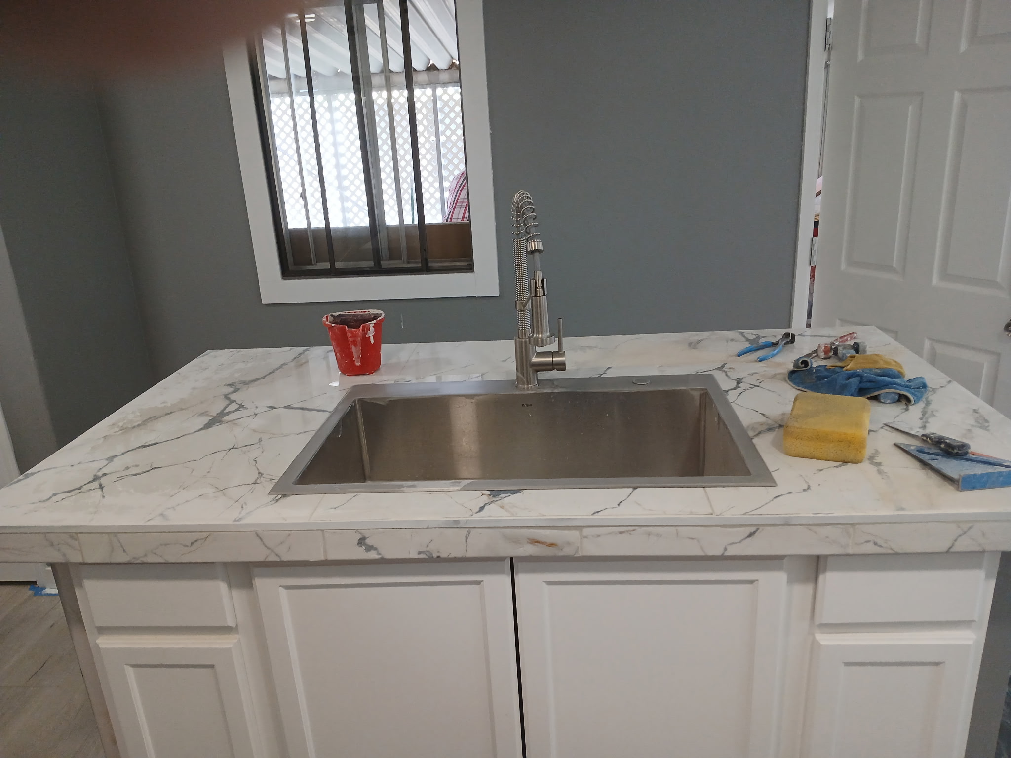 Completed kitchen island with white marble countertop and undermount stainless sink
